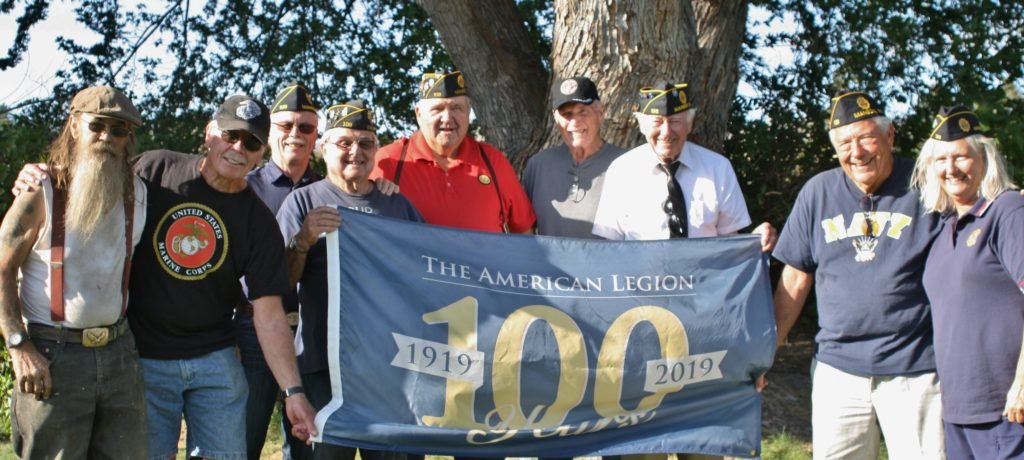 Members of American Legion Post 108 hold up flag celebrating 100 years of the American Legion
