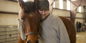 Male veteran and horse share a close moment; courtesy of VA: https://www.va.gov/salt-lake-city-health-care/stories/equine-assisted-therapy-helps-veterans/