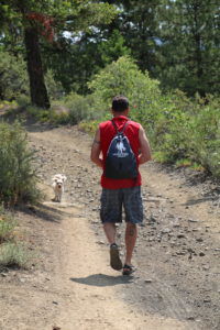 Rich Henning and his dog walking along foothills trails in central Washington; viewed from behind