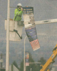 city worker installing banner on bracket