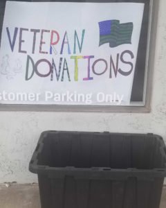 handwritten sign stating Veteran Dnoations above a black storage tote without lid