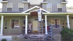 two painters working on the outside of a large home